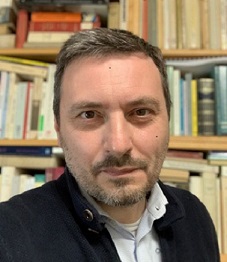 colour photo of Franco Pierno with background of bookcase of books