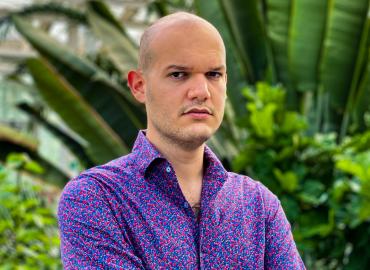 Image of Marco standing in front of greenery